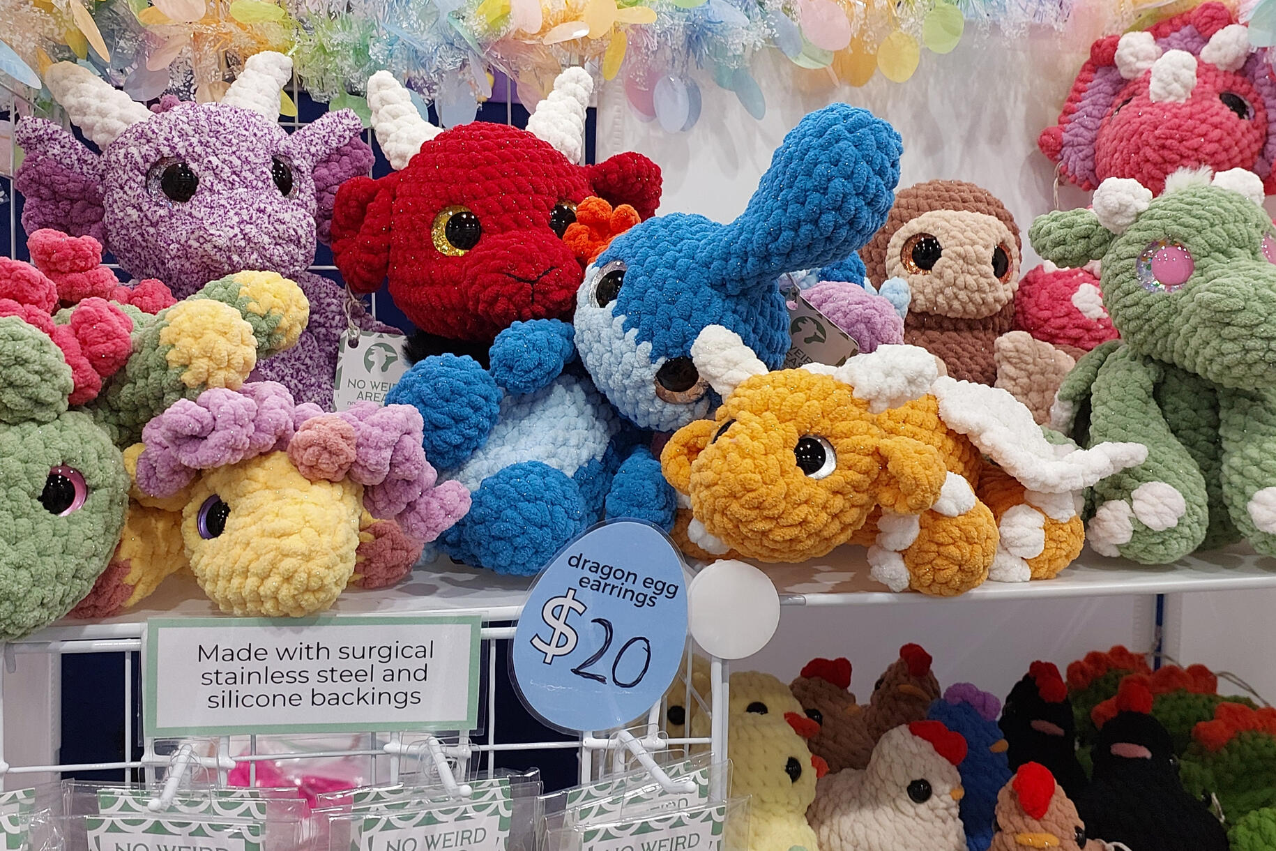 A collection of crocheted plushies sitting on top of a white wire shelf.