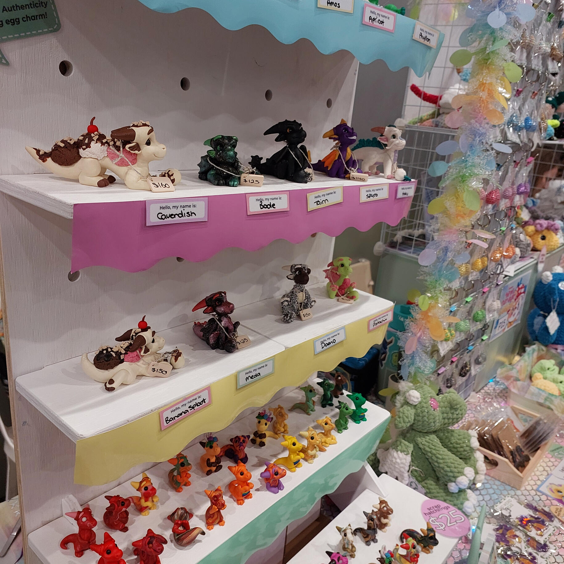 A collection of colourful polymer clay dragons sitting on top of a white shelf.